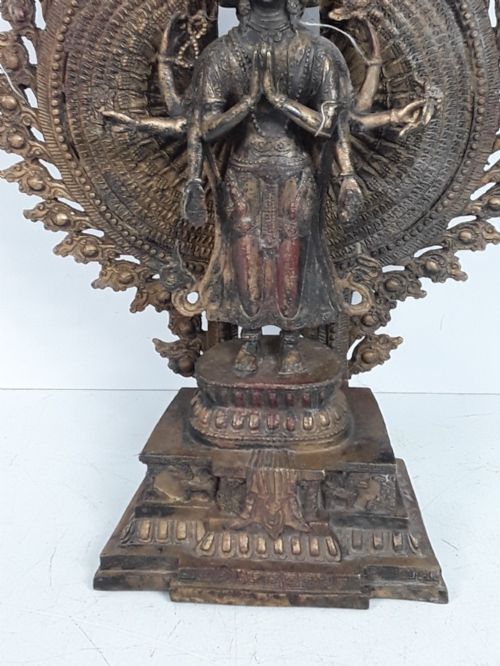 fig 2. A dark bronze Tibetan sculpture depicting eleven-headed Avalokiteshvara with radiating arms set against a halo mandorla on a lotus pedestal.