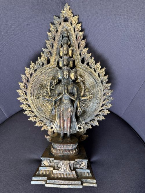 fig 6. A dark bronze Tibetan sculpture depicting eleven-headed Avalokiteshvara with radiating arms set against a halo mandorla on a lotus pedestal.