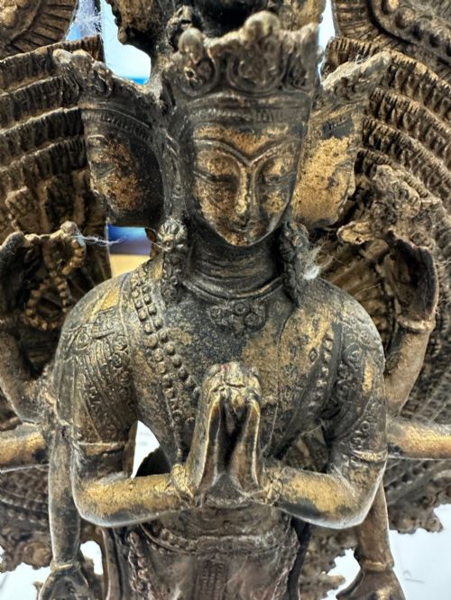 fig 7. A dark bronze Tibetan sculpture depicting eleven-headed Avalokiteshvara with radiating arms set against a halo mandorla on a lotus pedestal.
