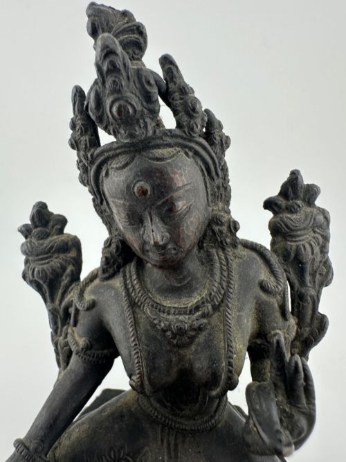 fig 2. A dark bronze figure of the Buddhist deity Tara seated in lalitasana on an ornate lotus base.