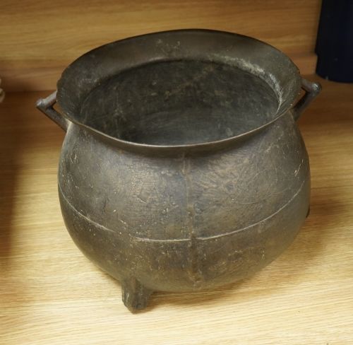 fig 2. A 17th-century leaded bronze cauldron with a bulbous body, three short feet, angular side handles, and a dark patinated surface.