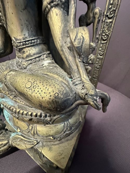 fig 2. An antique cast bronze figure of Green Tara seated on an elaborate throne with a flaming halo backpiece and visible green patination.