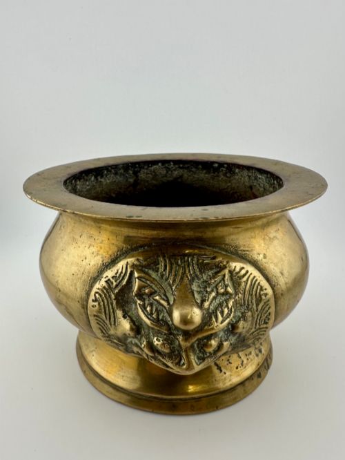 fig 1. A rounded antique brass Chinese censer featuring a flared rim, pedestal base, and sculpted lion mask handles on either side.