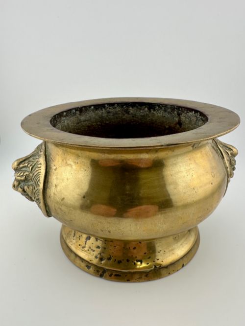 fig 2. A rounded antique brass Chinese censer featuring a flared rim, pedestal base, and sculpted lion mask handles on either side.