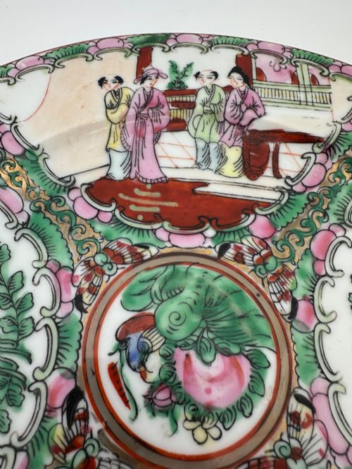 fig 1. A circular hand-painted ceramic charger with alternating panels depicting human figures and floral motifs in green, pink, and red enamels with gold accents.