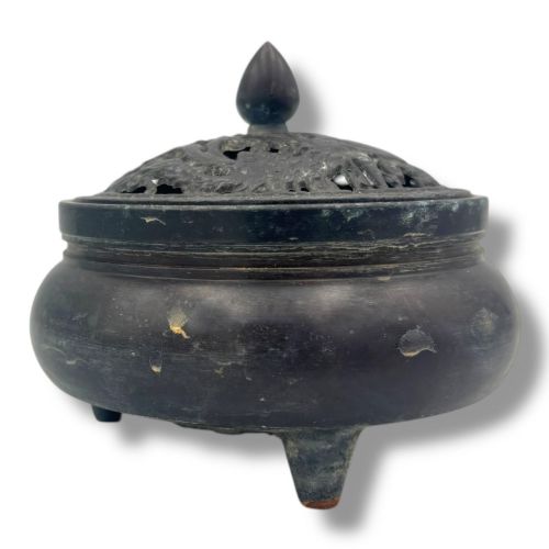 fig 1. A dark patinated bronze tripod censer featuring a rounded body, three short tapered feet, and a pierced openwork lid topped with a bud finial.