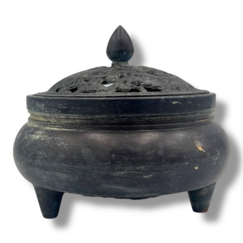 fig 3. A dark patinated bronze tripod censer featuring a rounded body, three short tapered feet, and a pierced openwork lid topped with a bud finial.