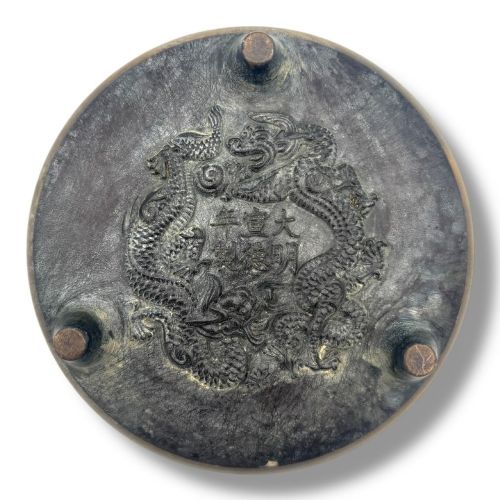 fig 3. A Chinese bronze tripod censer featuring a compressed circular body, three tapered feet, and a reticulated lotus lid topped with a pointed finial.