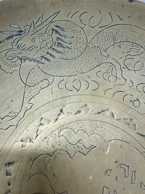 fig 4. A circular shallow brass dish featuring detailed hand-engraved designs of dragons, clouds, and a central circular motif.
