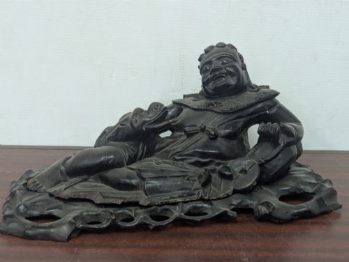 fig 1. A late Qing Dynasty dark carved hardwood figure depicting a reclining Budai resting on an openwork carved wooden base.