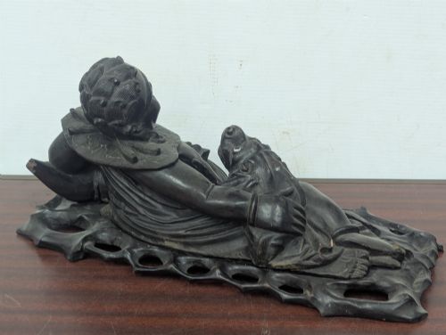 fig 3. A late Qing Dynasty dark carved hardwood figure depicting a reclining Budai resting on an openwork carved wooden base.