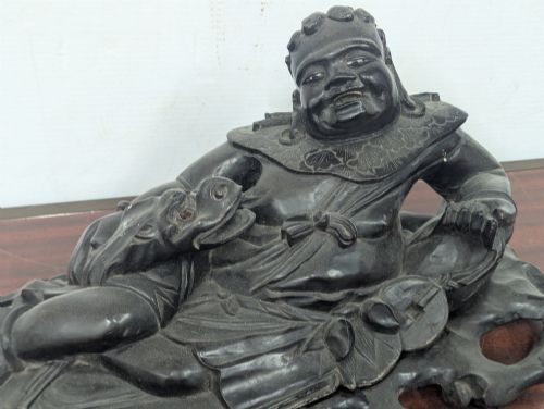 fig 4. A late Qing Dynasty dark carved hardwood figure depicting a reclining Budai resting on an openwork carved wooden base.