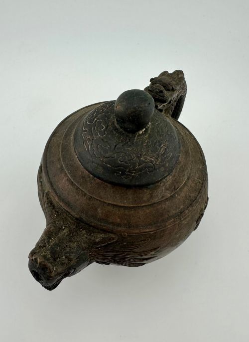 fig 2. A dark cast bronze Chinese teapot featuring a sculpted dragon handle, a dragon-head spout, and raised Chinese character carvings on the main body.