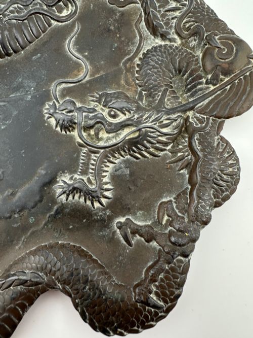 fig 1. A dark patinated metal tray featuring a raised relief carving of a Japanese dragon coiling around its organic rim.
