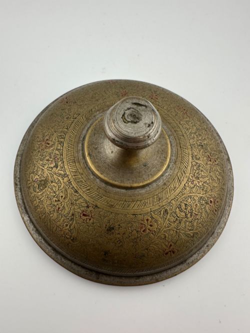 fig 2. An antique domed Indian brass hand gong with detailed floral engravings, a turned central finial handle, and a dark wooden striker.