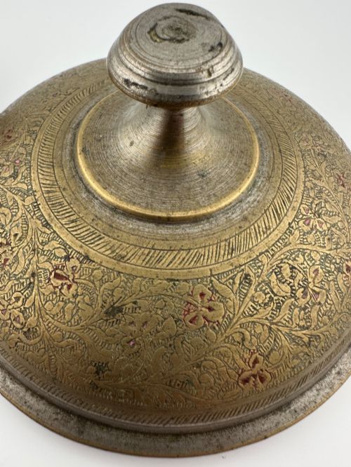fig 3. An antique domed Indian brass hand gong with detailed floral engravings, a turned central finial handle, and a dark wooden striker.