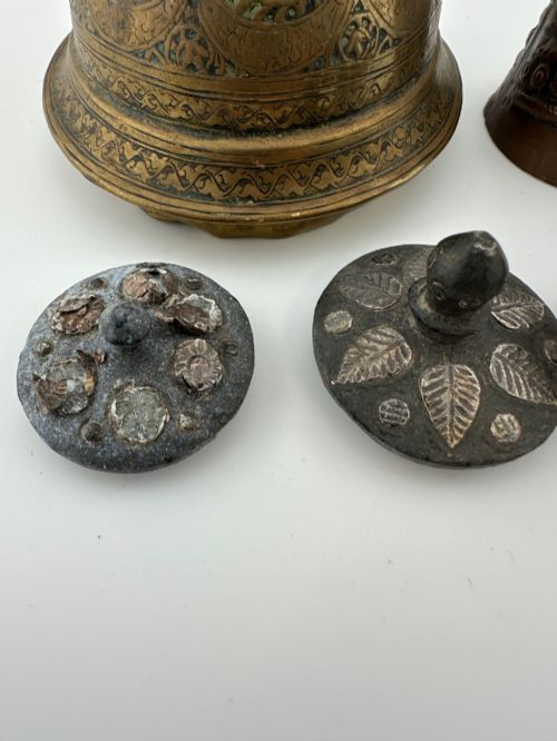 fig 4. A five-piece group of antique Persian Qajar metalware, including an engraved brass incense burner lid with a finial, a dark carved vessel collar, and three small circular lids.