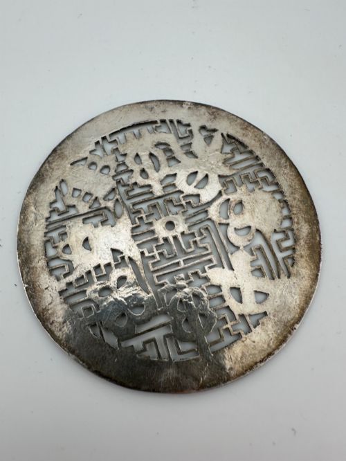 fig 1. A circular 19th-century Tibetan silver plaque featuring openwork fretwork and hand-engraved Buddhist auspicious symbols framed by a geometric border.