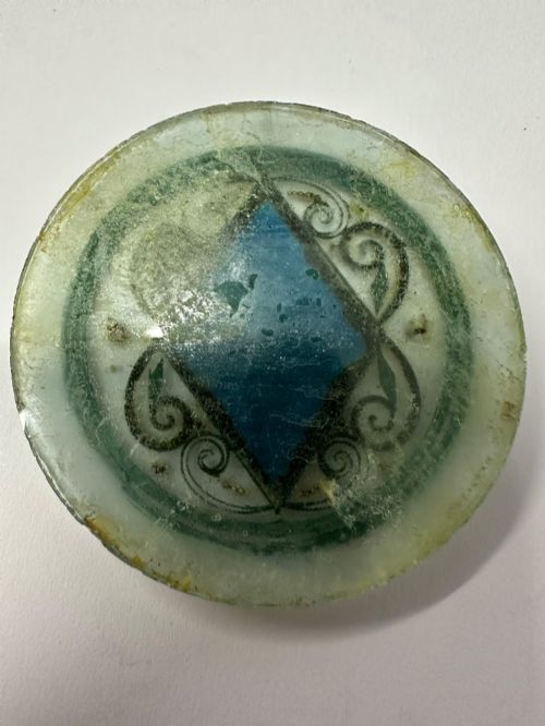 fig 2. A circular glass Ottoman roundel featuring delicate gilt filigree scrollwork and a central diamond-shaped blue medallion with a calligraphic tughra.