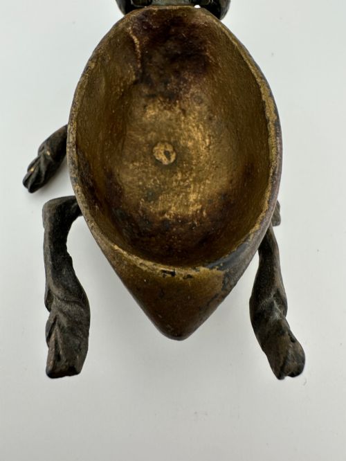 fig 4. A cast dark brass match holder sculpted in the detailed shape of a fly with textured wings, compound eyes, and six legs.