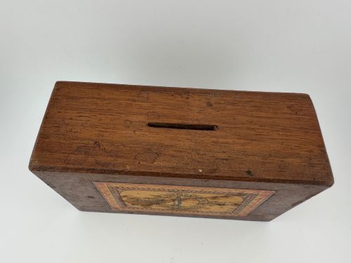 fig 4. A rectangular dark wooden church collection box featuring a coin slot on top and a printed yellow and red Society for the Propagation of the Gospel label on the front.