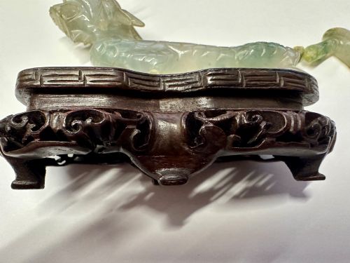 fig 1. A carved pale green jade dragon sculpture shown alongside a dark pierced hardwood display stand.