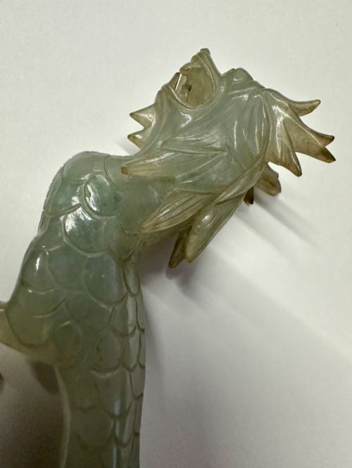fig 2. A carved pale green jade dragon sculpture shown alongside a dark pierced hardwood display stand.