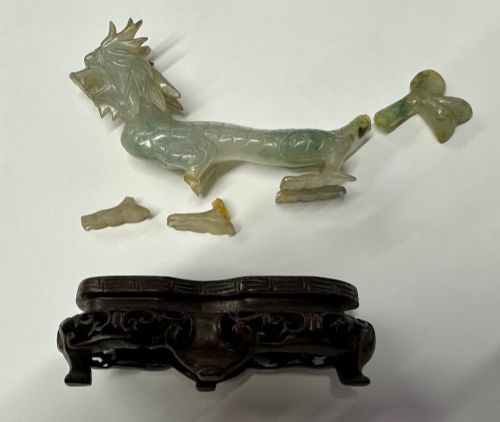 fig 4. A carved pale green jade dragon sculpture shown alongside a dark pierced hardwood display stand.