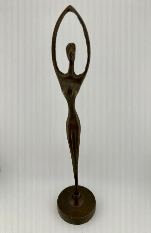 fig 1. A slender modernist bronze sculpture depicting an abstract female dancer with raised arms set upon a round metal base.