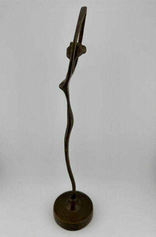 fig 2. A slender modernist bronze sculpture depicting an abstract female dancer with raised arms set upon a round metal base.