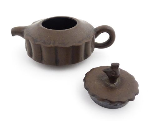 fig 3. A small dark brown unglazed ceramic teapot featuring a lobed body and a bird-shaped finial on the lid.