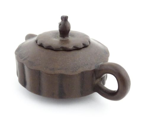 fig 4. A small dark brown unglazed ceramic teapot featuring a lobed body and a bird-shaped finial on the lid.