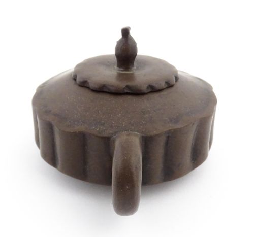 fig 5. A small dark brown unglazed ceramic teapot featuring a lobed body and a bird-shaped finial on the lid.