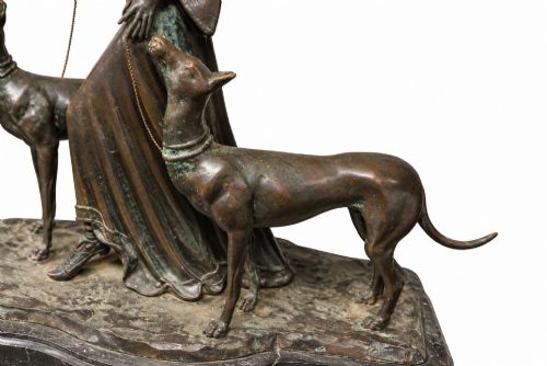 fig 2. A dark bronze Art Deco sculpture depicting a stylised woman walking two greyhounds on thin chains, set on a dark polished marble base.