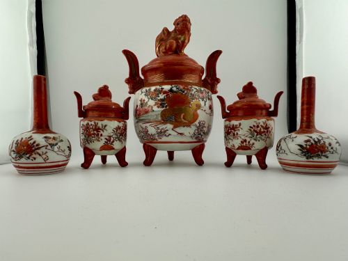 fig 1. A five-piece Japanese Kutani porcelain garniture set featuring three tripod censers with shishi lion lids and two bottleneck vases in iron-red and polychrome enamel detailing.