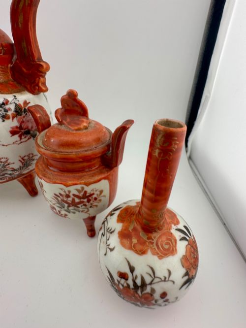 fig 2. A five-piece Japanese Kutani porcelain garniture set featuring three tripod censers with shishi lion lids and two bottleneck vases in iron-red and polychrome enamel detailing.