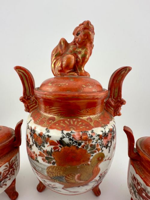 fig 3. A five-piece Japanese Kutani porcelain garniture set featuring three tripod censers with shishi lion lids and two bottleneck vases in iron-red and polychrome enamel detailing.