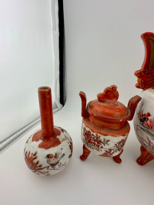 fig 4. A five-piece Japanese Kutani porcelain garniture set featuring three tripod censers with shishi lion lids and two bottleneck vases in iron-red and polychrome enamel detailing.
