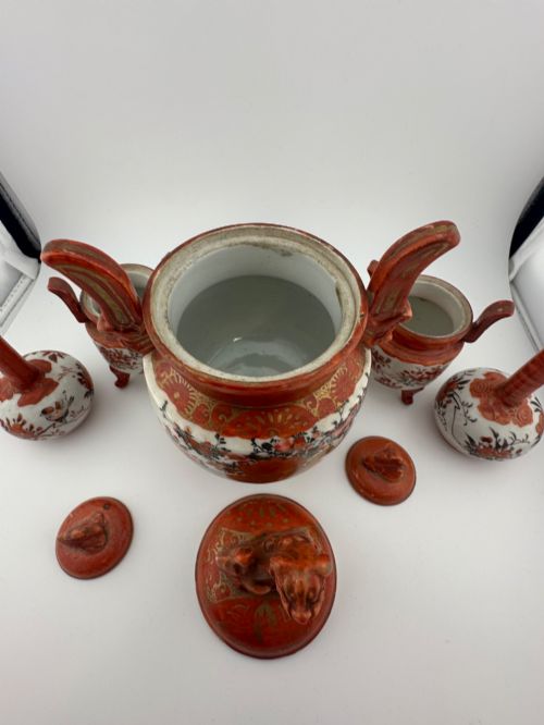 fig 5. A five-piece Japanese Kutani porcelain garniture set featuring three tripod censers with shishi lion lids and two bottleneck vases in iron-red and polychrome enamel detailing.