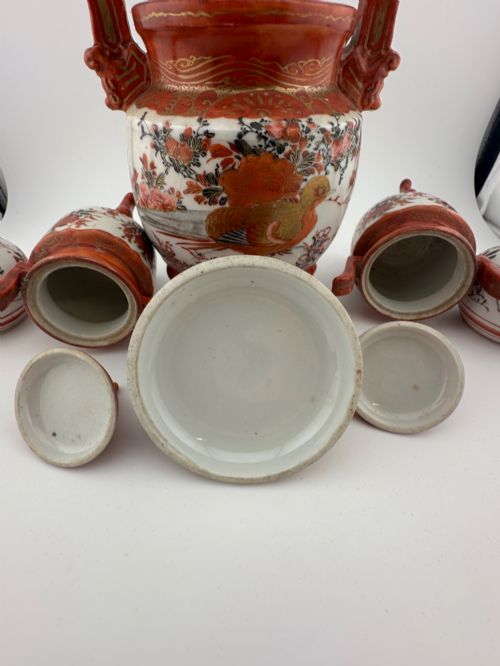 fig 6. A five-piece Japanese Kutani porcelain garniture set featuring three tripod censers with shishi lion lids and two bottleneck vases in iron-red and polychrome enamel detailing.