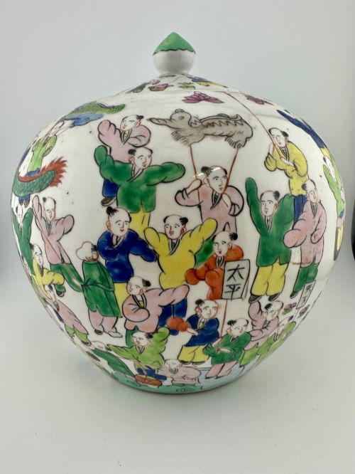 fig 1. A rounded white porcelain covered jar featuring hand-painted colourful enamels depicting a dragon festival procession with children.