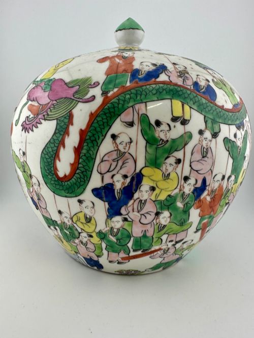 fig 4. A rounded white porcelain covered jar featuring hand-painted colourful enamels depicting a dragon festival procession with children.