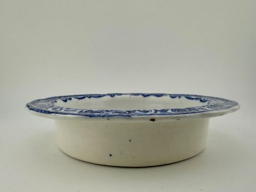 fig 2. A circular blue and white transferware ceramic dish featuring a central printed depiction of abbey ruins framed by a decorative scrolled border.