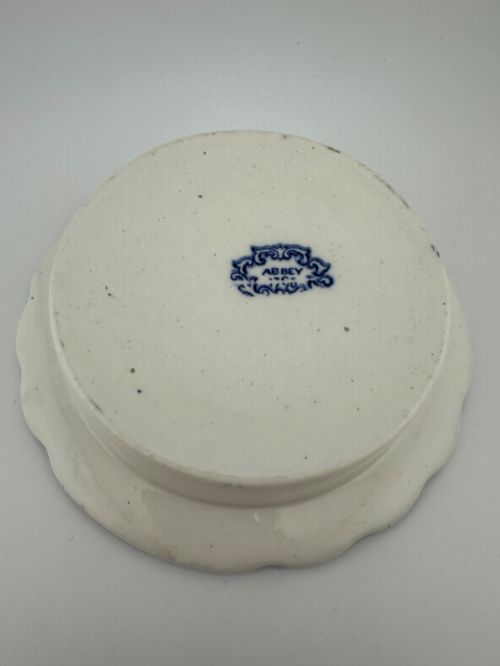 fig 3. A circular blue and white transferware ceramic dish featuring a central printed depiction of abbey ruins framed by a decorative scrolled border.