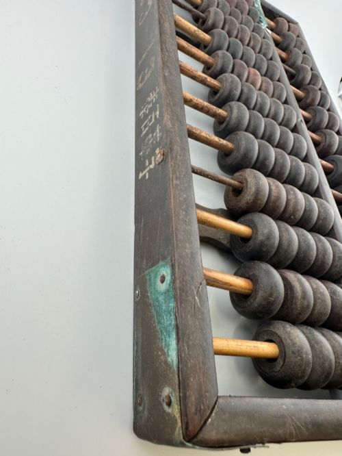 fig 1. A rectangular dark hardwood Chinese suanpan abacus with two upper beads and five lower beads per rod, reinforced with oxidised brass plates.
