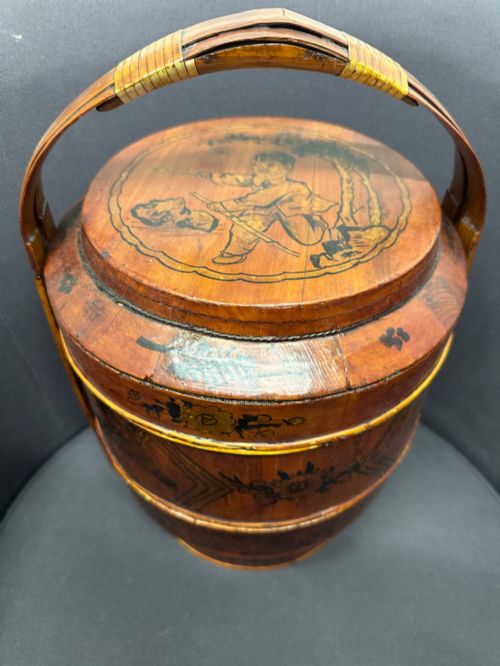 fig 1. A three-tiered late 19th-century Chinese bamboo and wood food carrier with an arched handle, featuring hand-painted yellow flowers, birds, and goldfish against a warm brown lacquer finish.