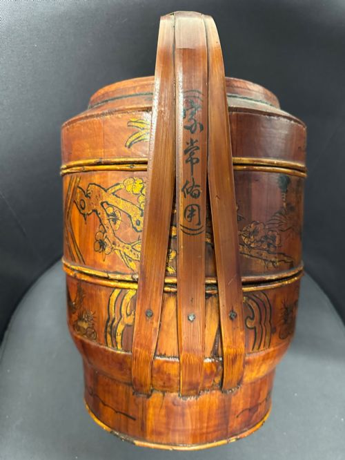 fig 3. A three-tiered late 19th-century Chinese bamboo and wood food carrier with an arched handle, featuring hand-painted yellow flowers, birds, and goldfish against a warm brown lacquer finish.