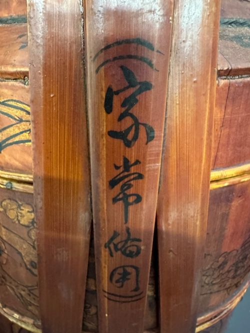 fig 4. A three-tiered late 19th-century Chinese bamboo and wood food carrier with an arched handle, featuring hand-painted yellow flowers, birds, and goldfish against a warm brown lacquer finish.