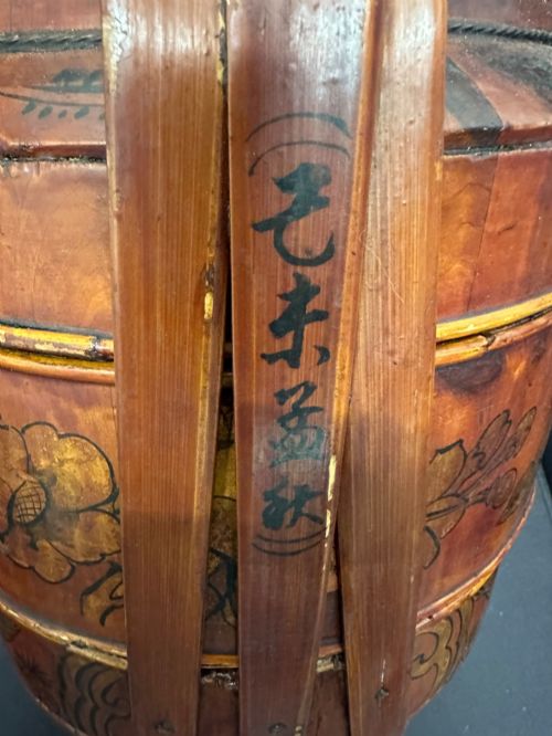 fig 5. A three-tiered late 19th-century Chinese bamboo and wood food carrier with an arched handle, featuring hand-painted yellow flowers, birds, and goldfish against a warm brown lacquer finish.