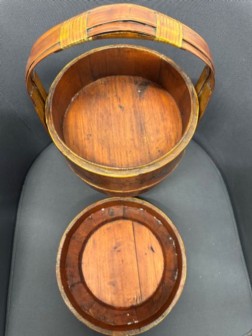 fig 7. A three-tiered late 19th-century Chinese bamboo and wood food carrier with an arched handle, featuring hand-painted yellow flowers, birds, and goldfish against a warm brown lacquer finish.
